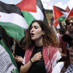 Crowd marching holding Palestinian flags