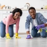 A woman and a man cleaning the floor in the kitchen