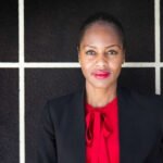 Black woman wearing a black suite jacket with a red blouse and red lipstick