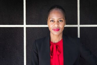 Black woman wearing a black suite jacket with a red blouse and red lipstick