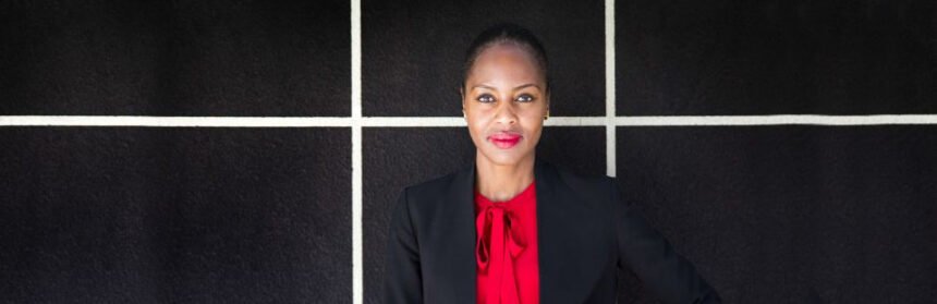 Black woman wearing a black suite jacket with a red blouse and red lipstick