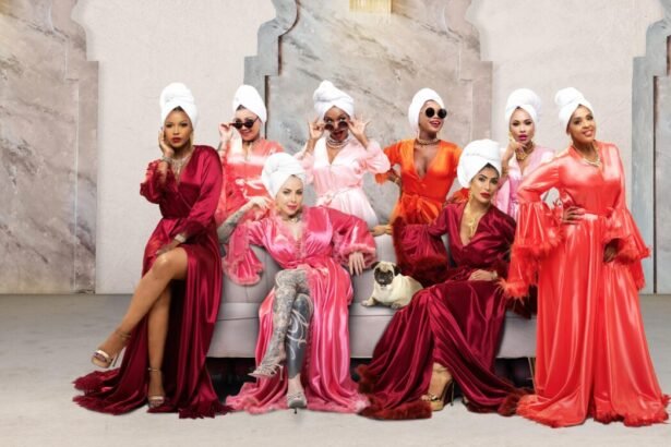 Eight women stand wearing stain gowns with towels wrapped on their heads and shades on