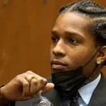 Black man with cornrows wearing black suite in court