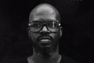 Black man with black glasses and a black background