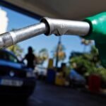 Petrol pump being held at a garage with a car in the background